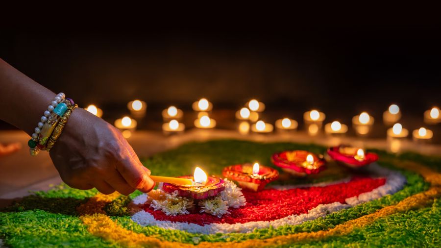 A bangled hand lighting numerous candles on a decorated table