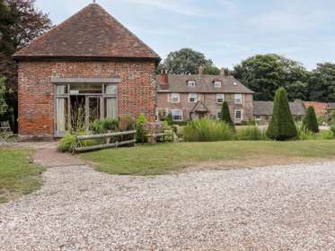 Exterior of a large old house set in garden with trees.