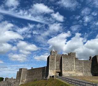 The fortress walls of Dover Castle with a blue sky and fluffy clouds