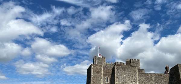 The fortress walls of Dover Castle with a blue sky and fluffy clouds