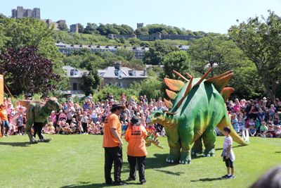 Two large dinosaur models with a crowd of people