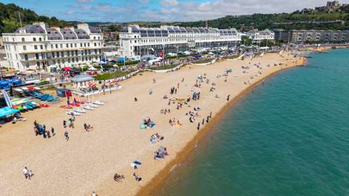 A sunny day on Dover harbour beach, with stalls along the promenade