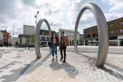 Large metal hoops set in paving with two people standing between