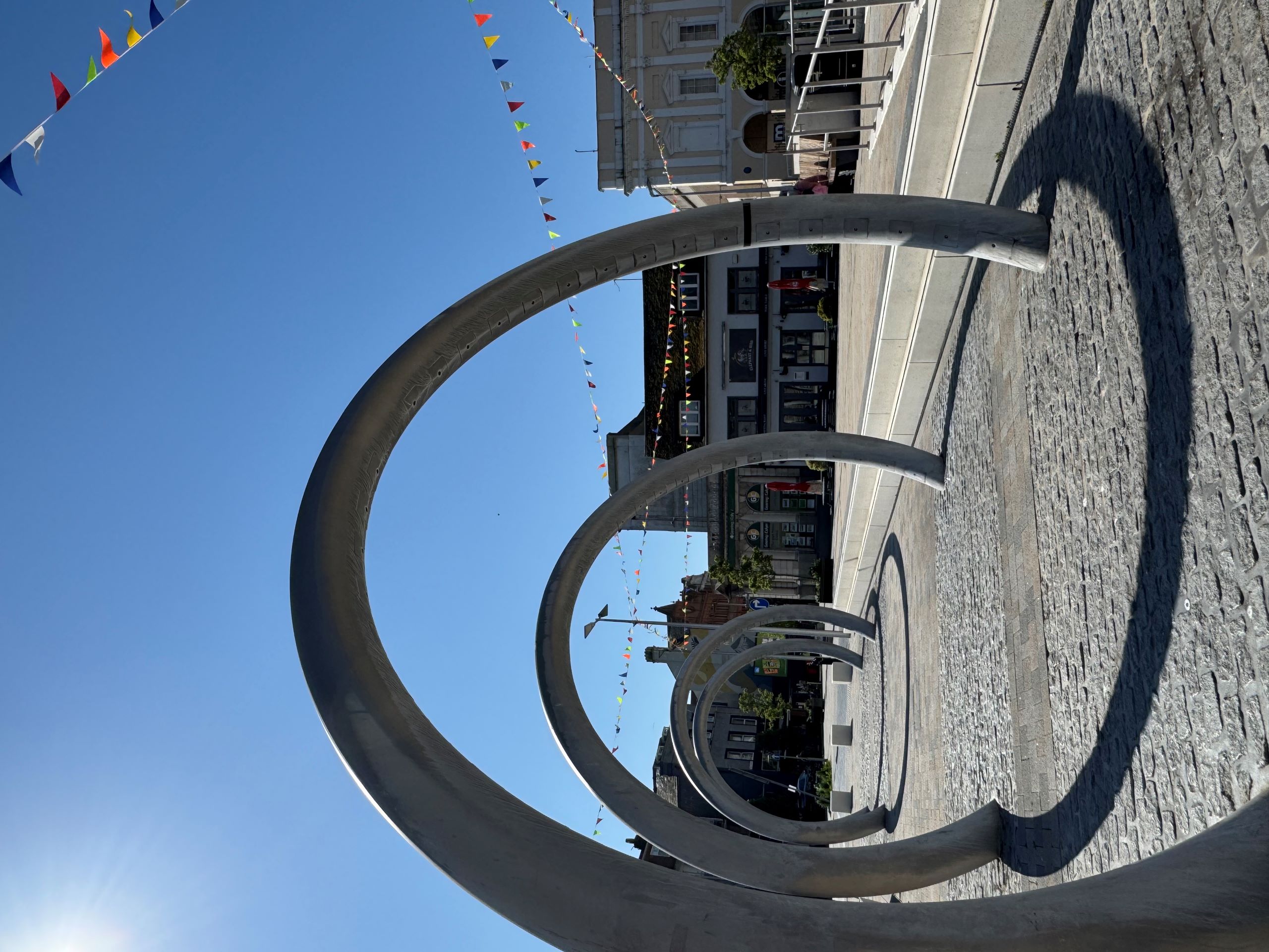 Large metal hoops in paving, bunting and blue sky.