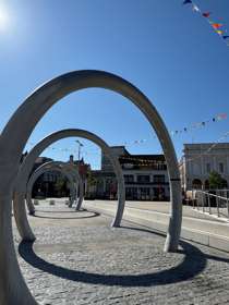 Large metal hoops in paving, bunting and blue sky.