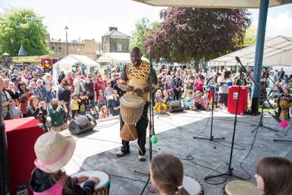 A crowd gathered round a stage where a man is playing drums.