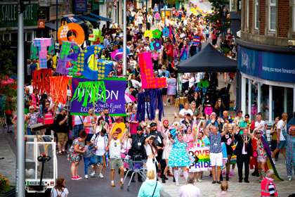 A colourful crowd walking through Dover streets with rainbow banners