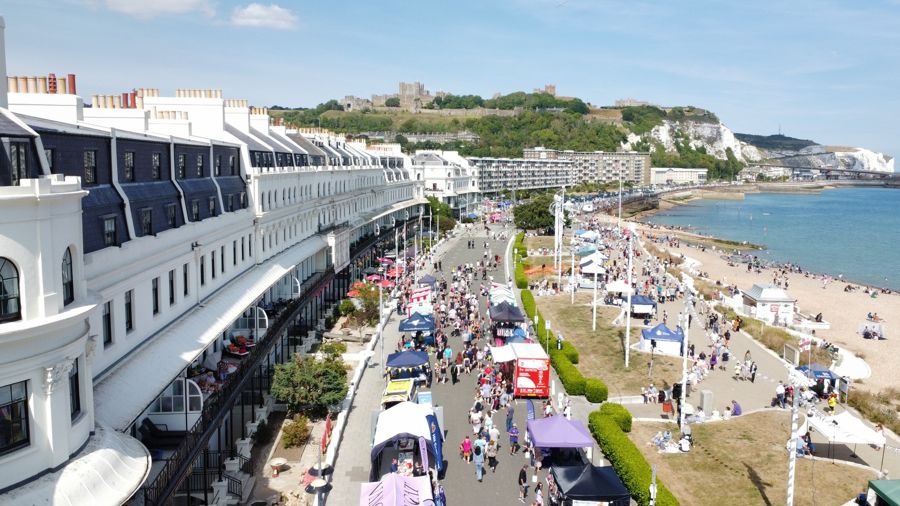 An aerial view of Dover seafront with stalls and crowds of people, the castle in the distance