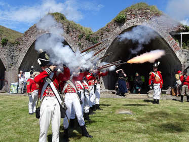 Re-enactors dressed as Napoleonic soldiers firing weapons. 