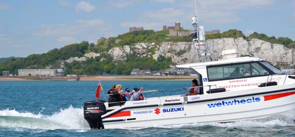Wetwheels boat with passengers heading out of Dover Harbour with Dover Castle and the white cliffs in the background