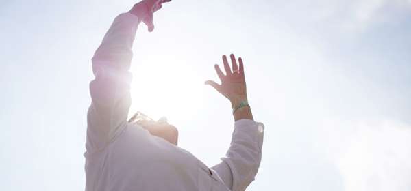 A person with their arms raised towards the sun.