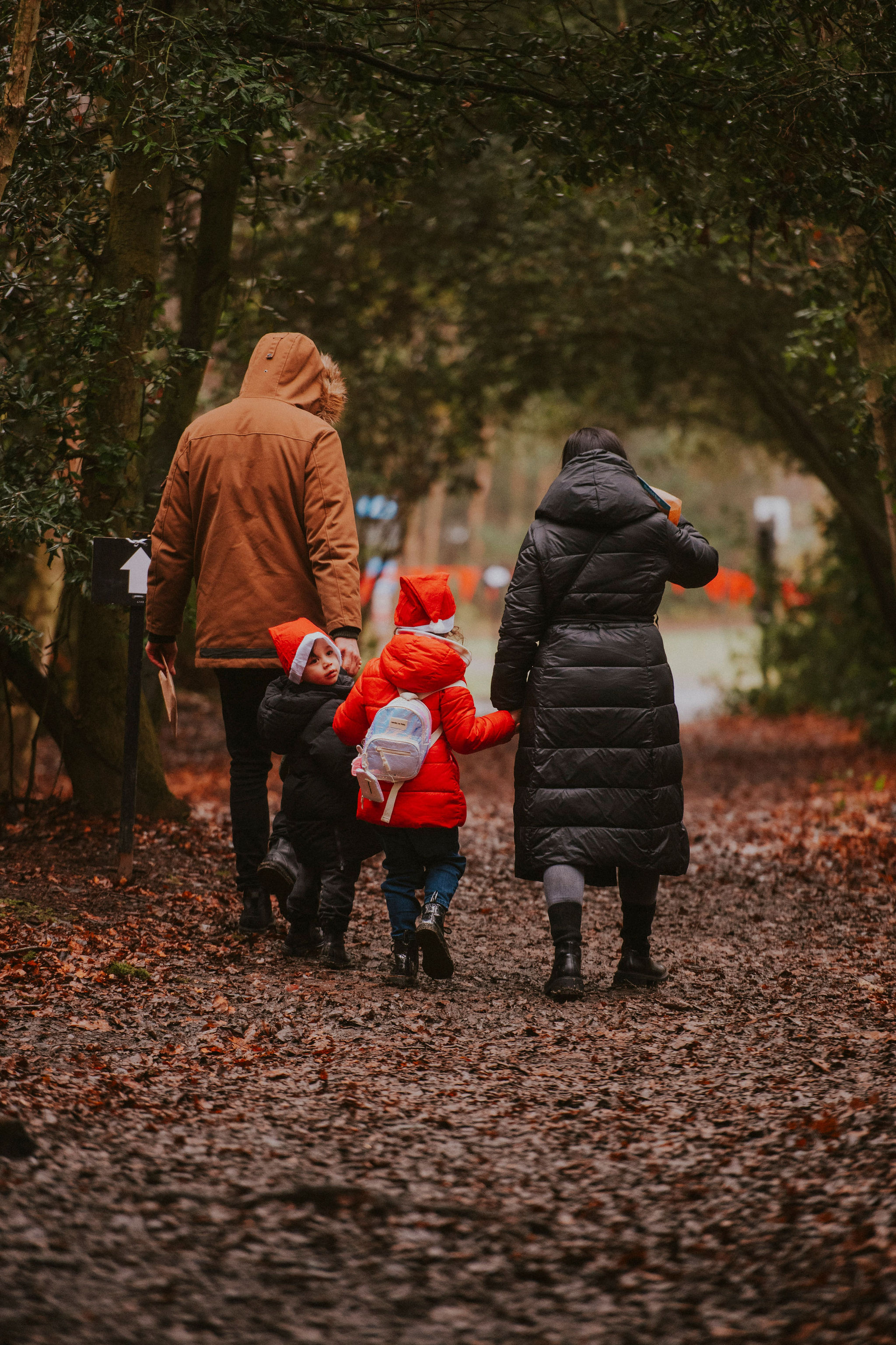 Two adults and a child walking through trees away from the camera.