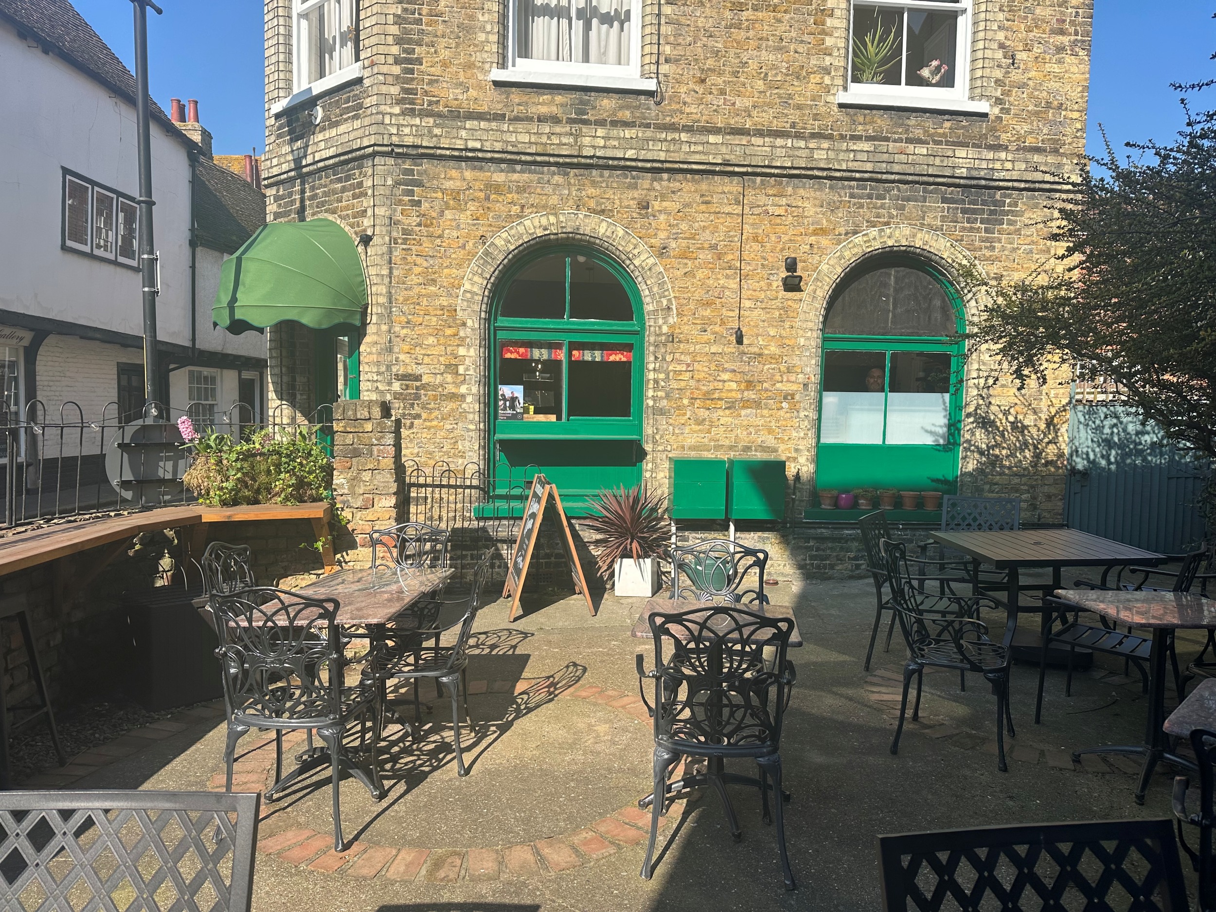 Exterior of premises painted green courtyard garden with tables and chairs