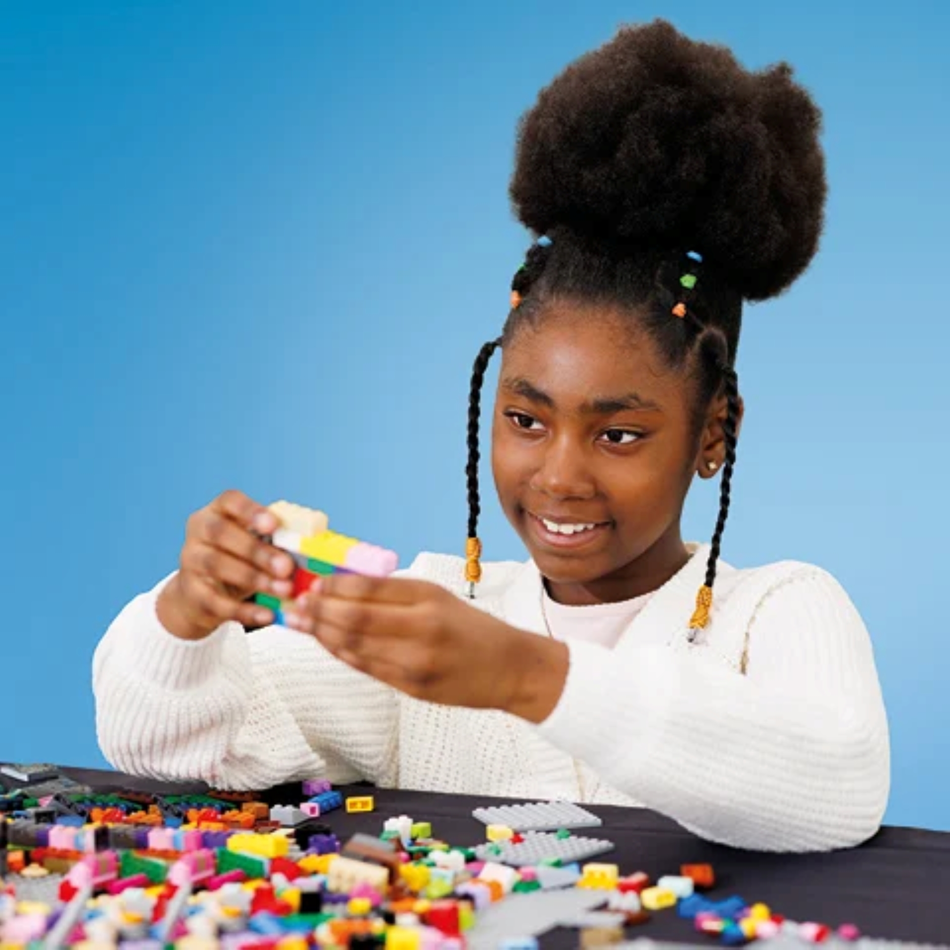 A girl sits playing with Lego bricks
