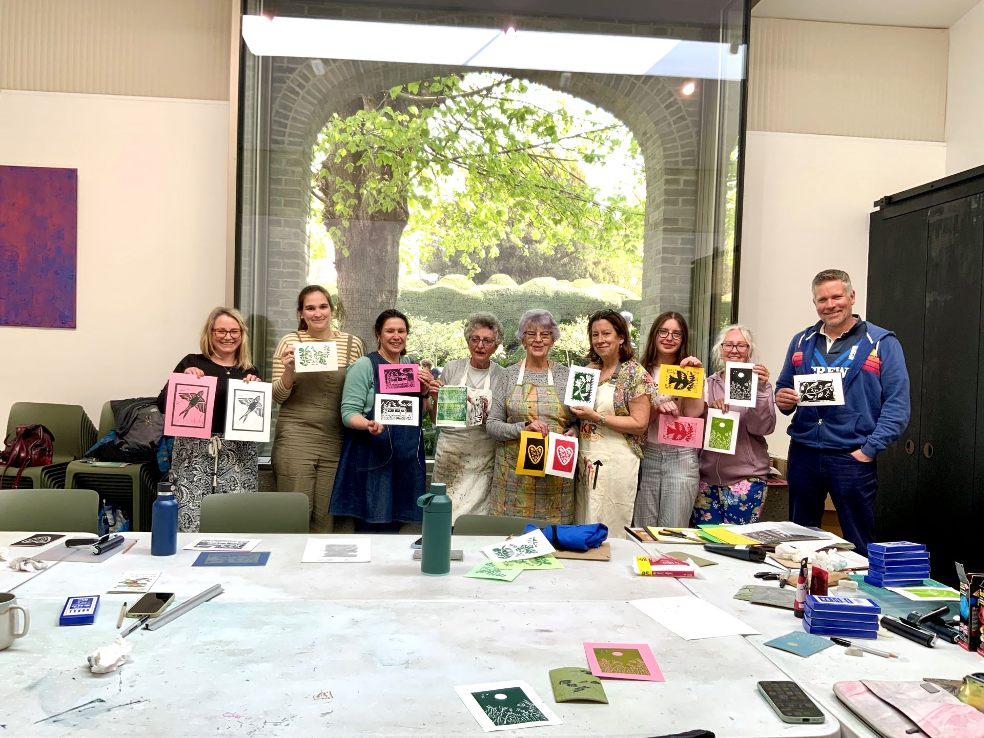 A group of people holding up artworks they've created.