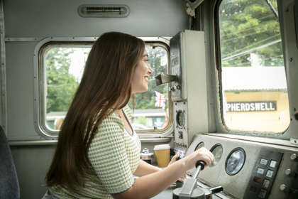 A woman inside the cab of a train learning to drive.