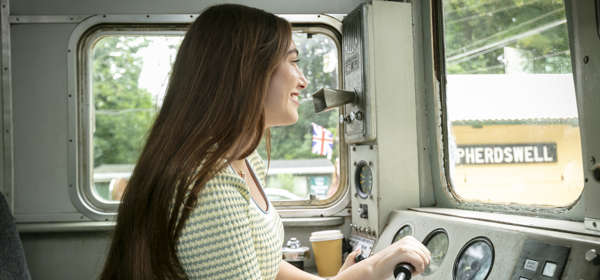 A woman inside the cab of a train learning to drive.