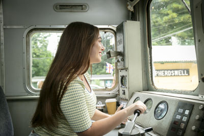 A woman inside the cab of a train learning to drive.