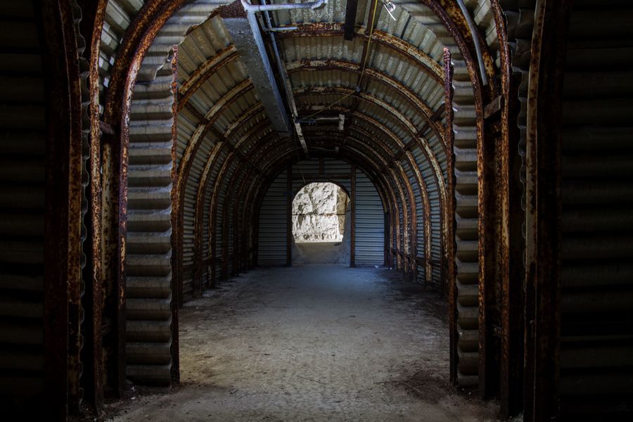 A corrugated metal-lined, arched tunnel with a chalk floor and chalk wall in the distance.