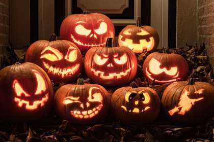 Nine carved jack-o'lantern pumpkins stacked in a doorway