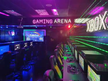 A row of gaming chairs, screens and equipment inside a gaming arena with neon lights on the walls