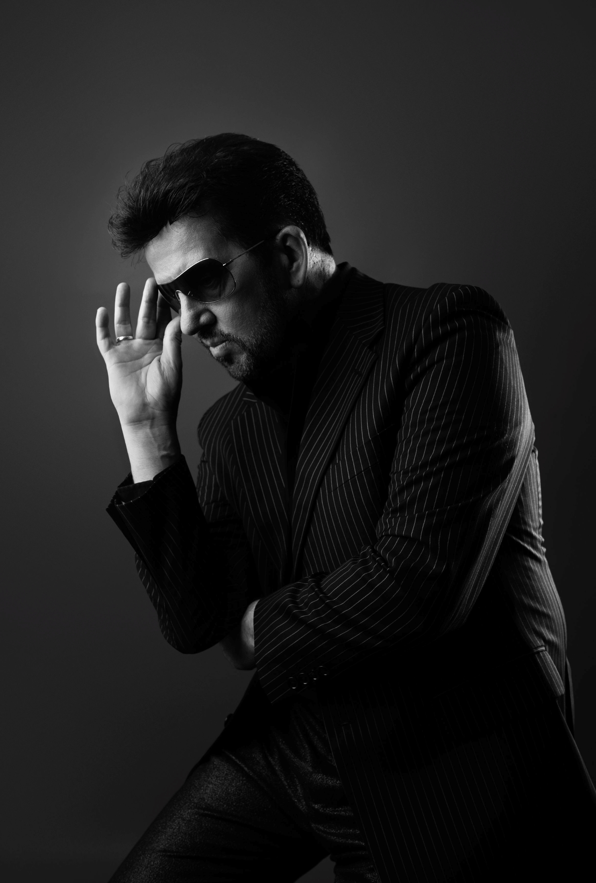 B & W shot of Steve posing as George Michael with his hand touching his sunglasses 