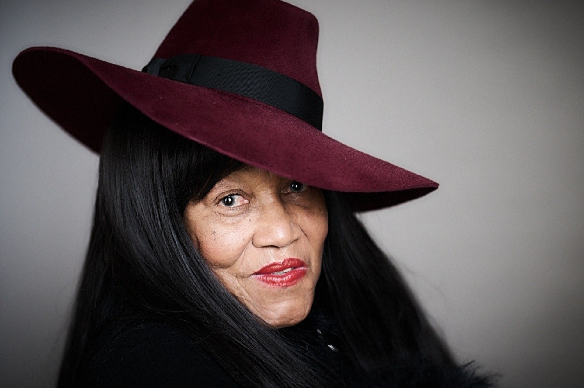 Head shot of Gloria wearing a maroon velvet hat