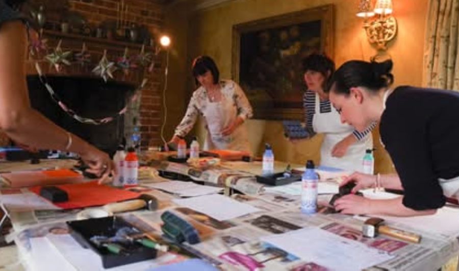 People round a table doing block printing on linen