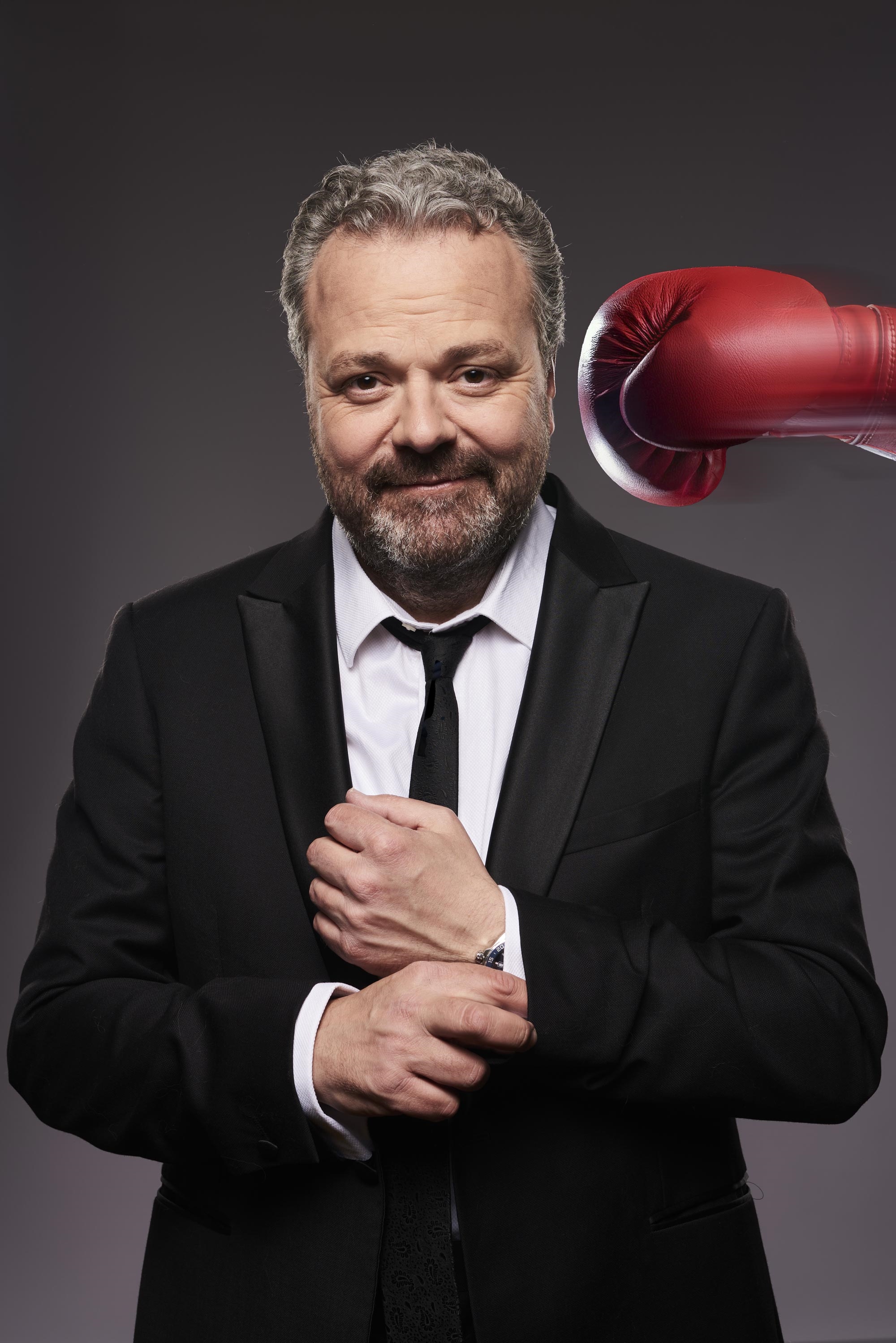 Hal dressed in a dinner suit with a red boxing glove aimed at the side of his head