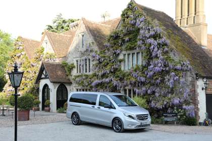 Silver Mercedes van outside wisteria-clad building