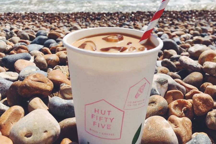 Cup of drink with a straw on a pebble beach