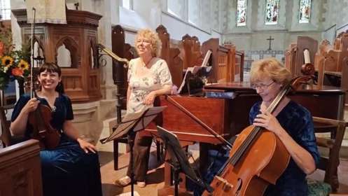 Three women playing classical instruments in a church