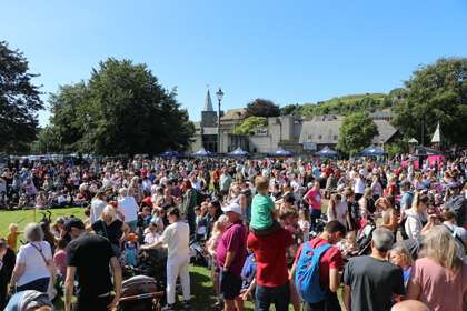 A crowd of adults and children in summer in Pencester Gardens.