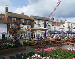 A pub and Georgian houses with hanging baskets and window boxes full of flowers.