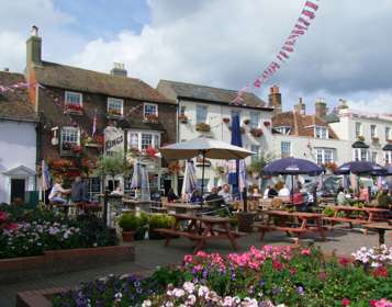 A pub and Georgian houses with hanging baskets and window boxes full of flowers.