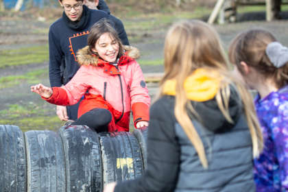 A group of children climbing over a row of tyres