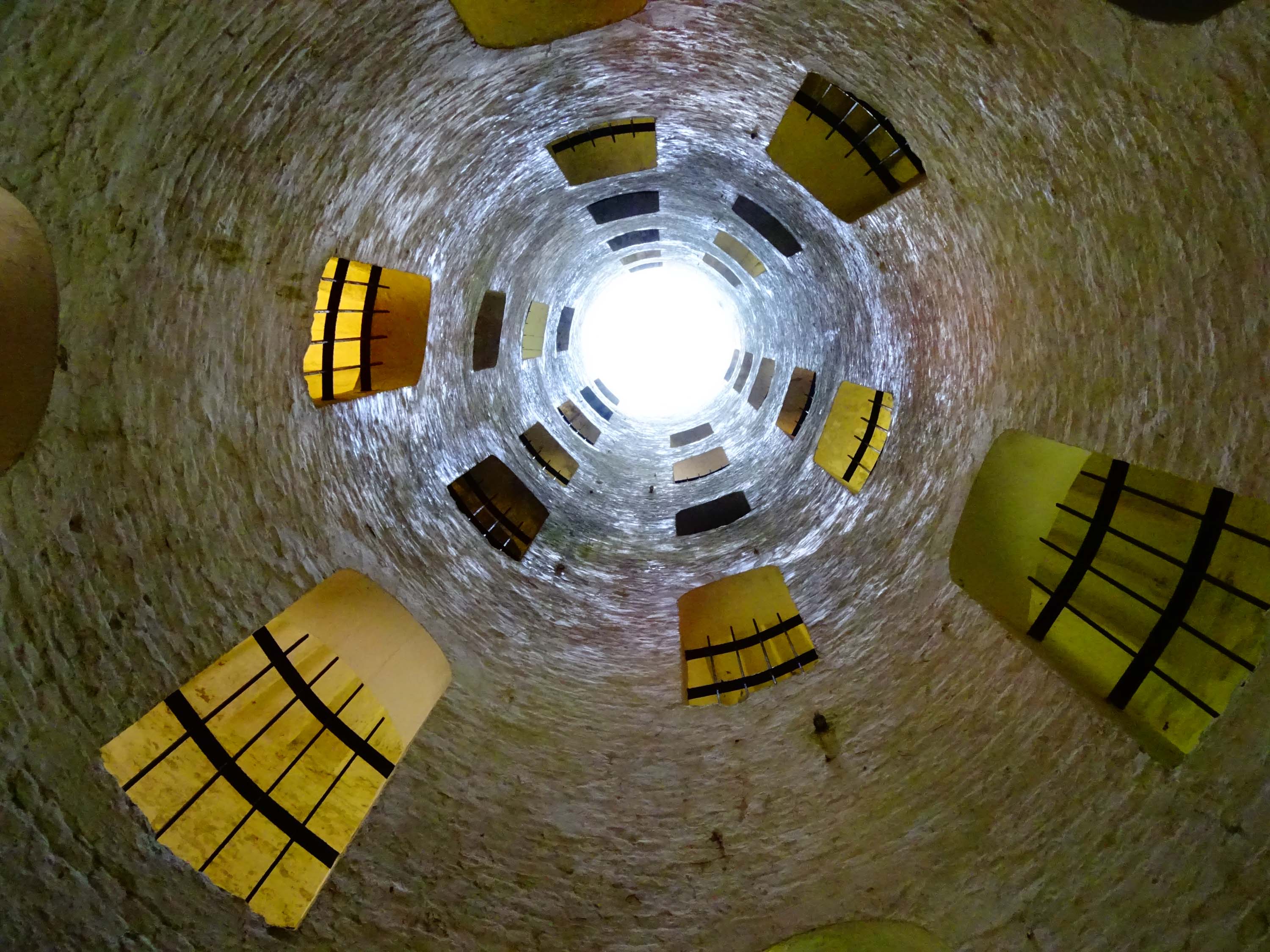 Looking up through a cylindrical staircase towards daylight