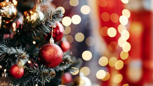 Close-up of a Christmas tree with sparkling red baubles and golden lights