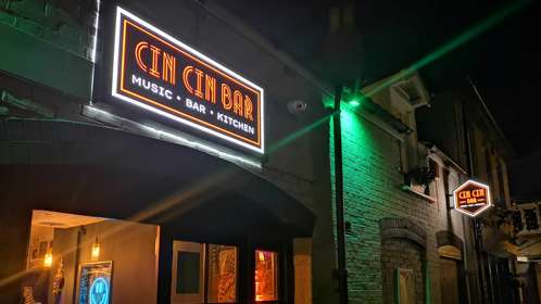 Entrance of Cin Cin bar at night with neon sign.