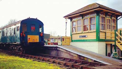 A heritage train next to a signal box signposted EYTHORNE