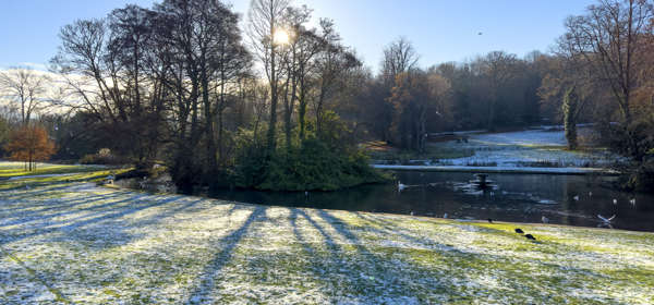 Kearsney Abbey lake in winter with a dusting of snow on the ground