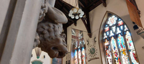 The main hall at Maison Dieu showing a gargoyle and the magnificent stained glass windows