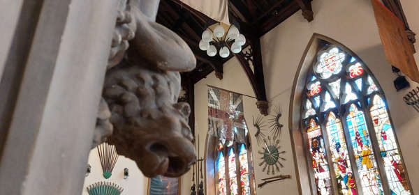 The main hall at Maison Dieu showing a gargoyle and the magnificent stained glass windows