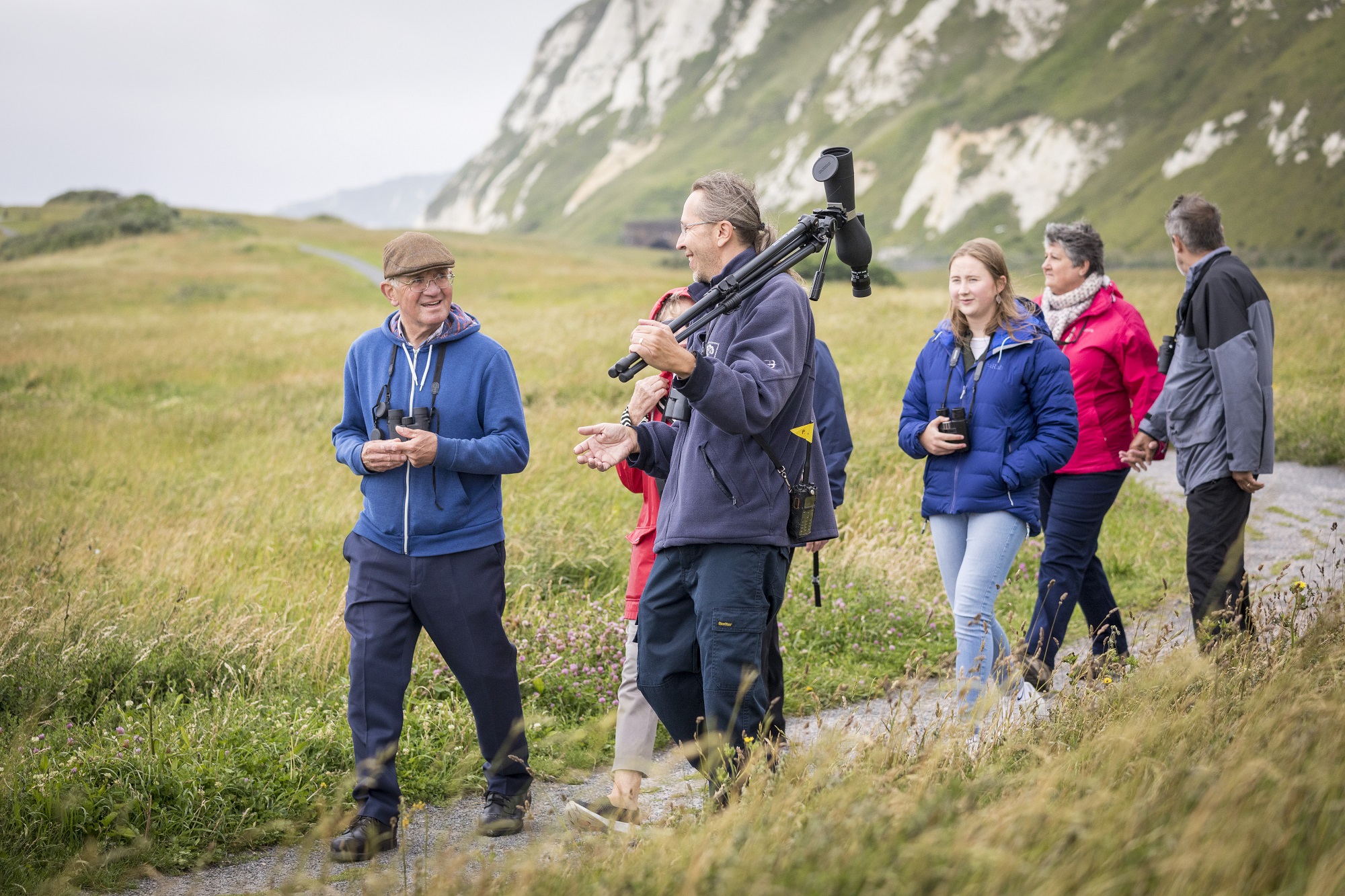 A man with a telescope leading a group of people on a path