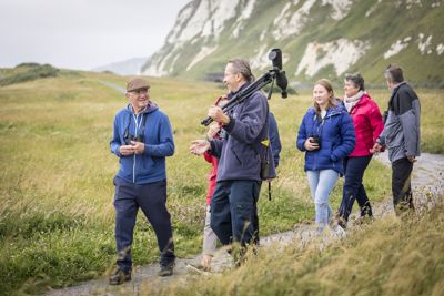 A man with a telescope leading a group of people on a path