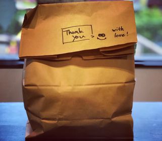 A brown paper takeaway back with the words 'Thank you - with love' written on.