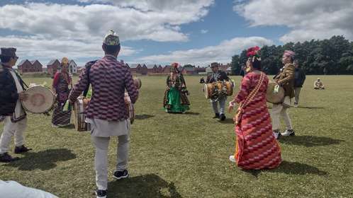 A group of dummers dressed in colourful outfits in a field