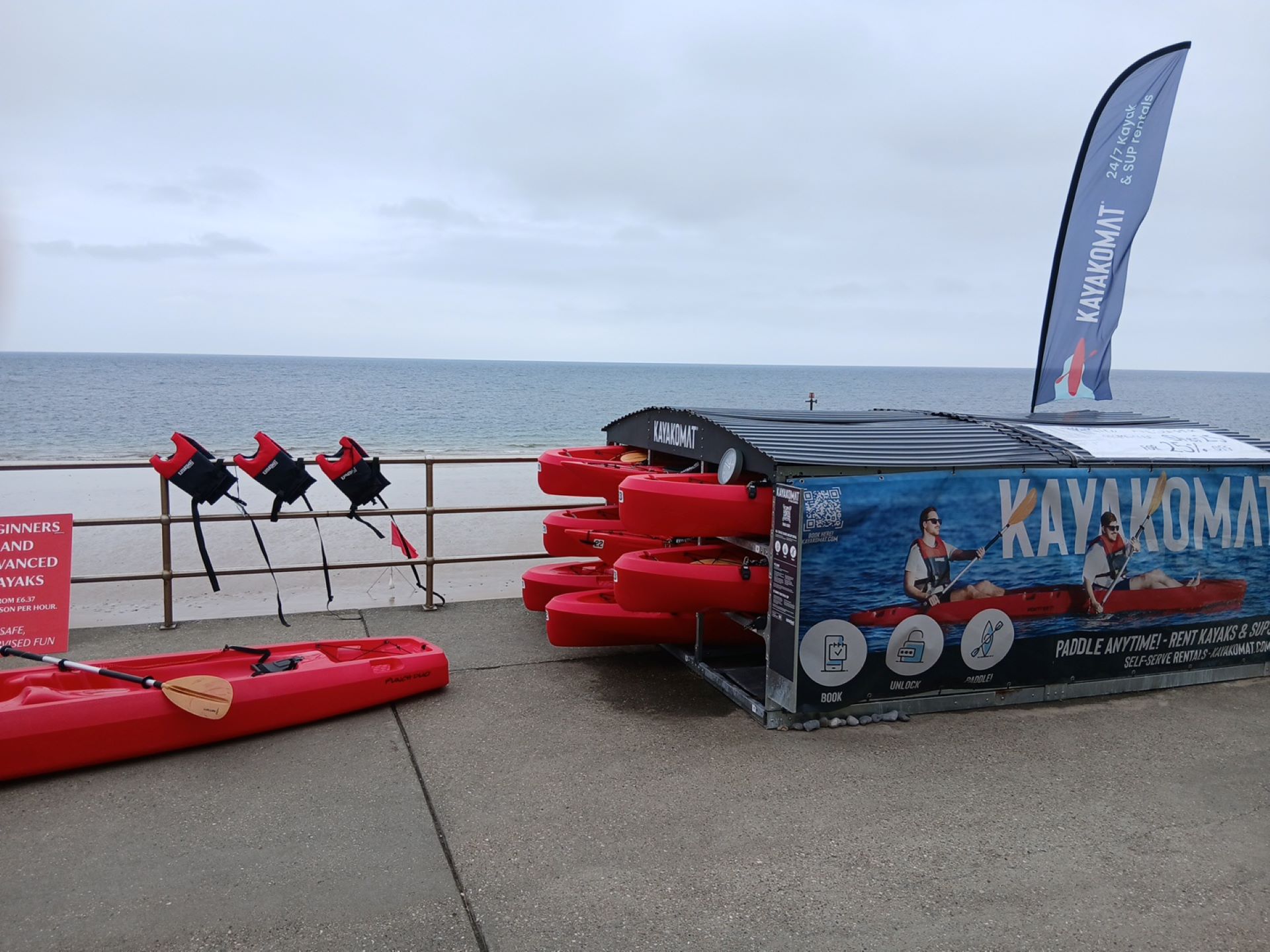 A self-service pod with red kayaks and SUPs