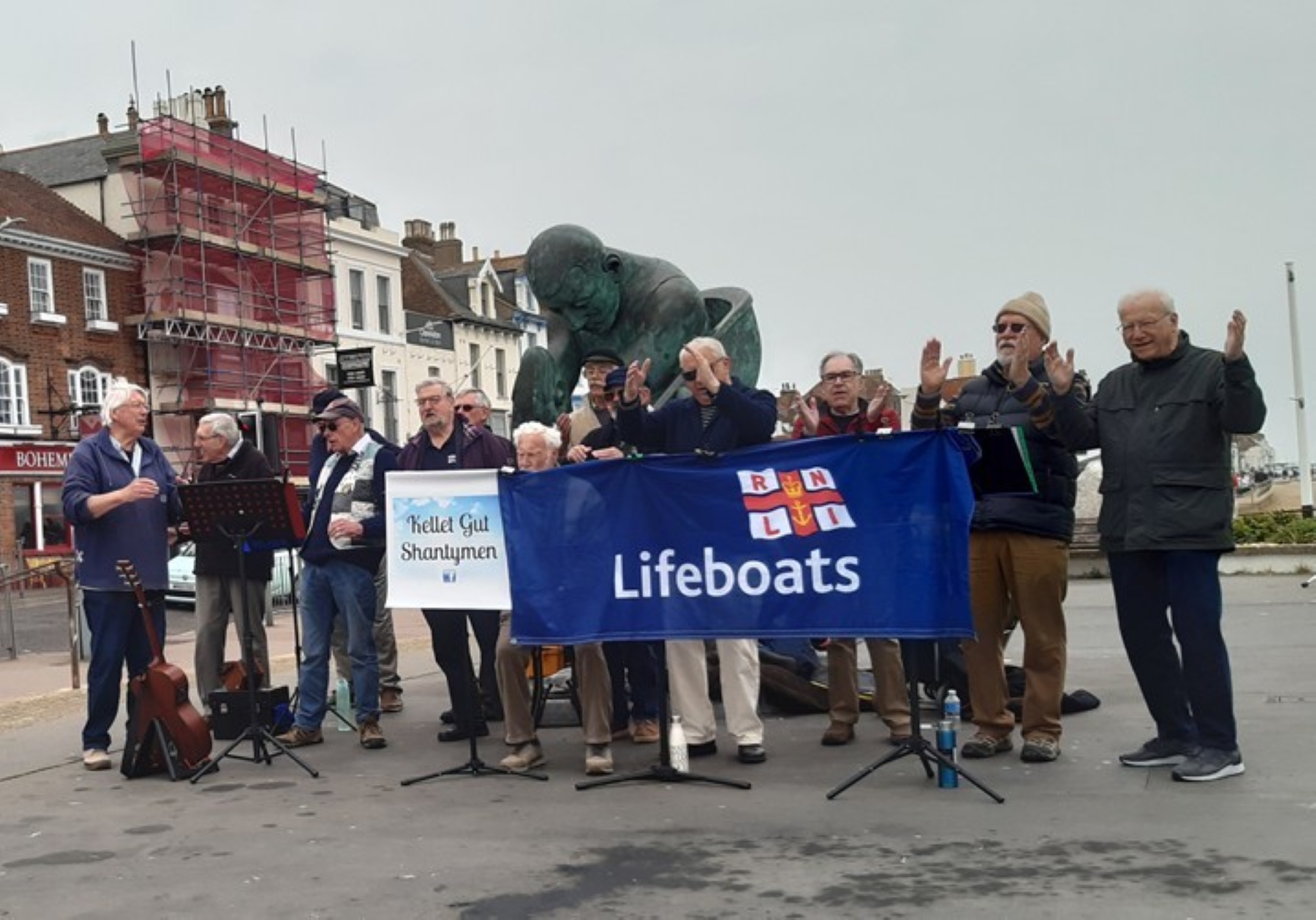 The members of Kellet Gut singing at Deal Pier holding a RNLI banner