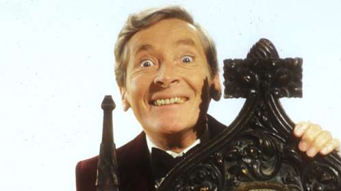 Head shot of Kenneth standing behind a wooden chair